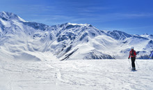 Skier On A Slope In Alpine Snowy Mountain Under Blue Sky