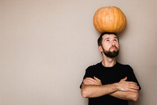Young Bearded Man In Black T-shirt Holding Small Pumpkin Above His Head
