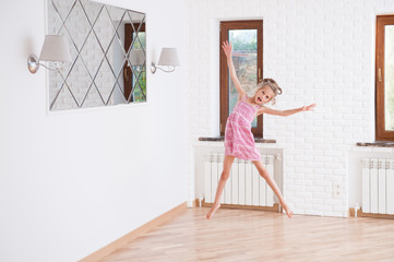 cute little slim girl jumping delightful indoors in new house with bright walls