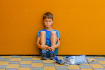 Wall Mural - Sad alone boy sitting near colorful wall outdoors