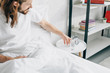 © LIGHTFIELD STUDIOS - selective focus of young bearded man with long hair having headache and taking glass of water in bedroom at home