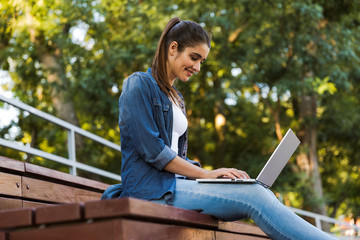 Poster - Amazing young beautiful woman sitting outdoors using laptop computer.