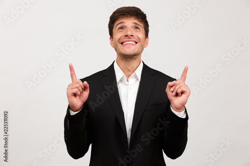 Cheerful young businessman standing isolated over white background wall pointing Poster Mural XXL