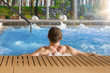 © Eskymaks - Handsome man in hot tub spa in luxurious hotel with big glass windows with nature view.