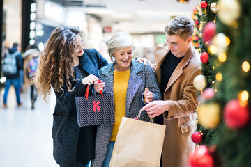 Wall Mural - A portrait of grandmother and teenage grandchildren in shopping center at Christmas.