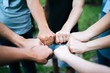 © Johnstocker - Close up of students standing hands making fist bump gesture.
