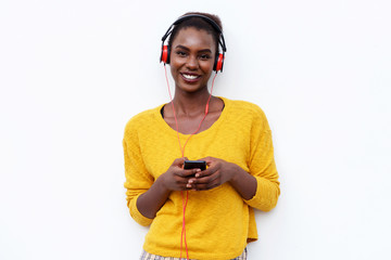 smiling young woman listening to music with headphones and mobile phone against isolated white background