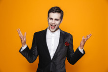 Photo Of Excited Zombie Man Wearing Groom Suit And Halloween Makeup Looking At Camera, Isolated Over Yellow Background