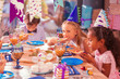 © zinkevych - Kids eating pizza. Calm thoughtful children attending birthday party and eating pizza at the big table
