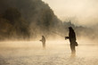 Men fishing in river with fly rod during summer morning.
