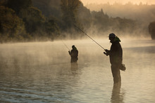 Men Fishing In River With Fly Rod During Summer Morning.
