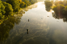 Aerial Shot Of A Man Fly Fishing In A River During Summer Morning.