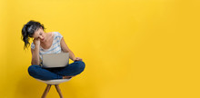 Young Woman Using Her Laptop On A Yellow Background