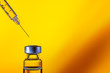 A syringe with the needle point to the vaccine vial on the colorful abstract background