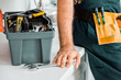 © LIGHTFIELD STUDIOS - cropped image of plumber leaning on kitchen counter and touching adjustable wrench in kitchen