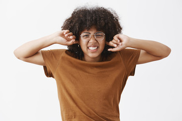 Wall Mural - cute good-looking female nerd with afro hairstyle in transparent prescribed glasses frowning and wri