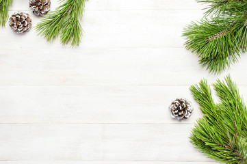 Christmas background, green pine branches, cones decorated with snow on white wooden table. Creative composition with border and copy space design top view. New Year's, holiday, christmas, decoration