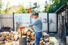 Man In Jeans And Checkered Shirt Standing Near Stump With Ax In Hands