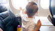 Photo of little toddler boy flying in airplane and touching illuminator