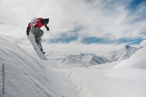 Dekoracja na wymiar  skaczacy-snowboardzista-trzymajacy-reke-na-snowboardzie-na-tle-gor-i-s