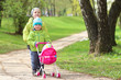 © dzmitrock87 - children's friendship. Small friends. Children walk in green park. Little boy and girl with toy carriage for doll. Brother and sister are together