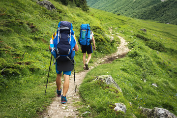Wall Mural - hiking trail in svaneti region, georgia. two hikers men walk on trek in mountain. tourists with back