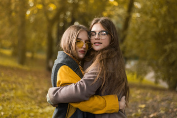 Two teenage girls are having fun in the park, autumn outfit. Funny girl friends throwing dry leaves in the city in autumn. Happy family on autumn walk!