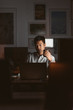 © mavoimages - Asian businessman drinking coffee while working in a dark office
