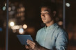 © mavoimages - Asian businessman standing in an office at night working online