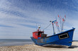 A blue fishing boat standing on the sandy shore of the sea.