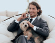 © ASDF - businessman holds his pet and talks on the smartphone while sitt