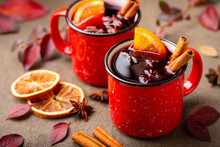 Two Cups Of Autumn Mulled Wine Or Gluhwein With Spices And Orange Slices On Rustic Table Top View. Traditional Drink On Autumn Holiday On The Background Of Autumn Leaves