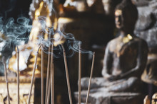 Incense Sticks Are Burning In Front Of An Altar With Buddha Figurines, Selective Focus