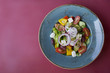 Greek salad in a blue plate on a claret background