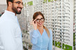 © puhhha - Optical Store. Eye Doctor Helping Woman Choosing Eyeglasses