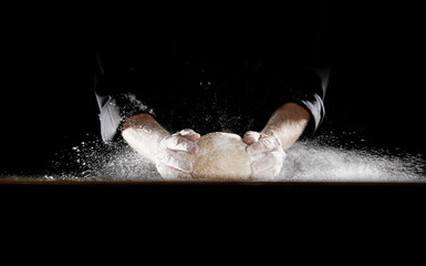 Man slamming dough into table causing flour to fly