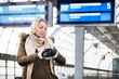 Woman looking at wristwatch in train station as her train has a delay, she is impassionate and late