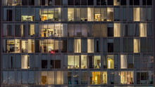 Windows Of The Multi-storey Building Of Glass And Steel Lighting Inside And Moving People Within Timelapse
