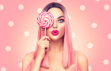 Beauty Sexy Model Woman With Trendy Pink Hairstyle And Beautiful Makeup Holding Lollipop Candy, On Pink Polka Dots Background