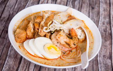 Wall Mural - Traditional rice noodles served with spicy broth cooked with coconut milk, topped with egg, prawn and fish cake. Laksa from Singapore.