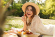 Smiling young girl in summer hat having a picnic