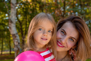 Lovely young mom and daughter in warm sunny summer day. Happy family mother and child little daughter playing and walking in the Park and enjoying the beautiful nature.