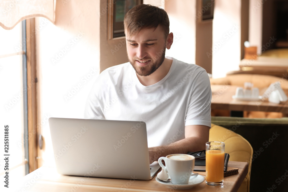 Young freelancer with laptop working in cafe