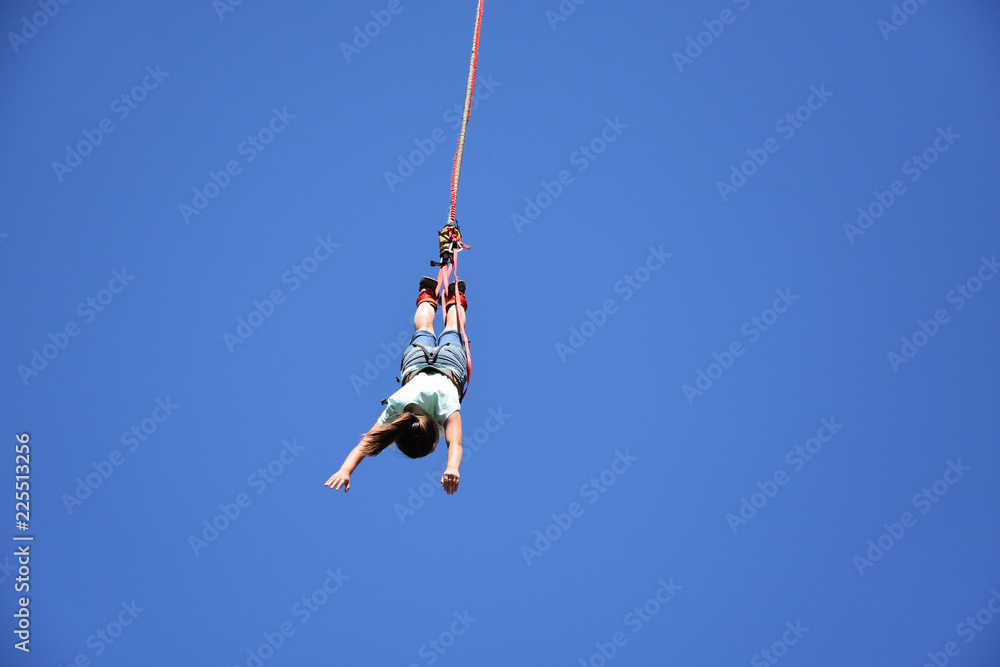 Bungee jumping from crane. Seen from the ground young woman hanging on ...