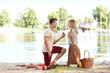 © Pixel-Shot - Young man making proposal to his girlfriend on romantic date near river