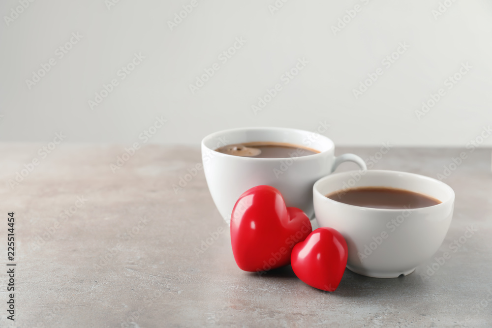 Cups of hot chocolate with red hearts on grey table