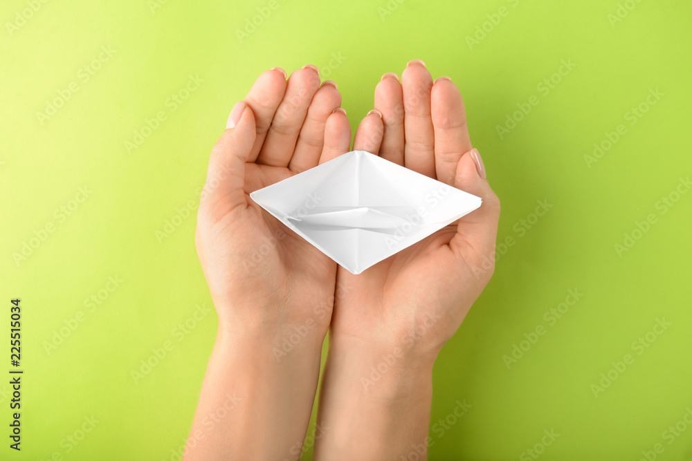 Woman with origami boat on color background