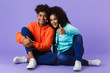 © Drobot Dean - Happy young cute african couple posing isolated over violet background showing thumbs up gesture.