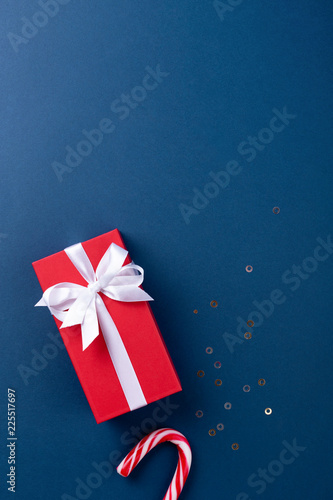 Christmas gift wrapped in red paper tied with white ribbon, and candy cane lo...