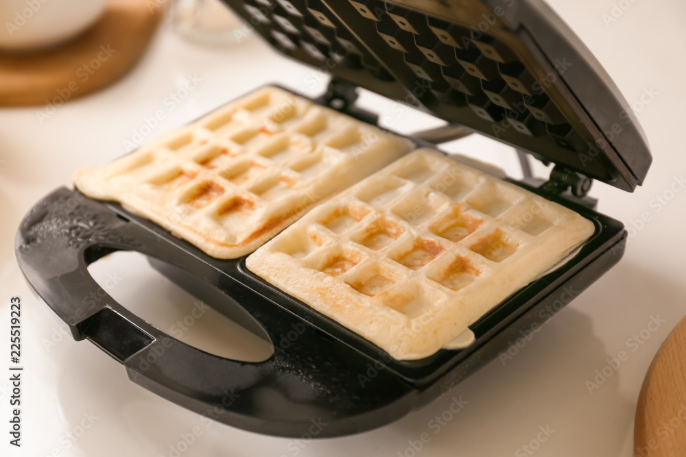 Waffle iron with fresh wafers on kitchen table